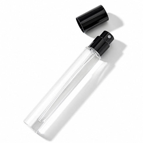 A clear glass perfume bottle with a black cap is shown against a white background.